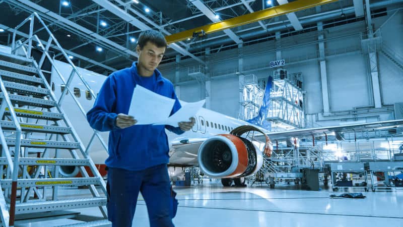 Ein Ingenieur arbeitet in einer Flugzeug-Fertigungshalle in Hamburg indem er sich Pläne ansieht.